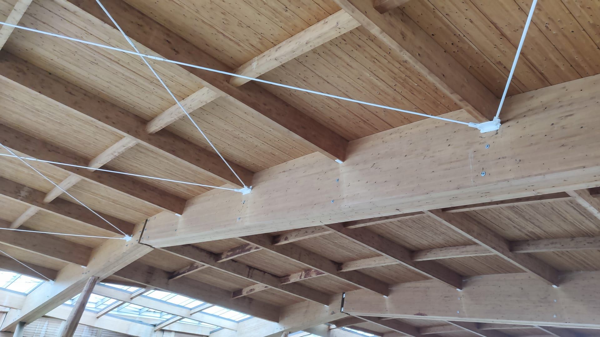 Vigas de madera laminada de una cubierta reforzadas con tirantes de acero, vistas desde abajo